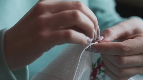 Hands Sewing White Fabric with Needle