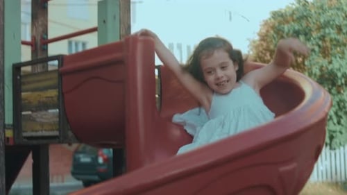 Girl Playing on a Slide in an Urban Playground