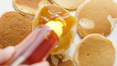 The pancake rotates, I pour honey on it, slow motion. Splashes of honey