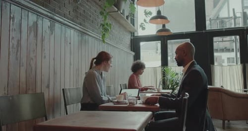 Coworkers having a Meeting in a Cafe using Digital tablet