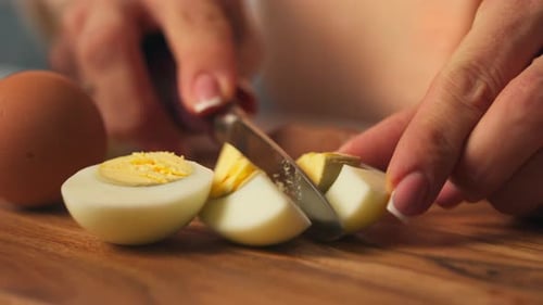 Close-up Of Female Hands Slicing Hard-boiled Egg On Wooden Board - Easter Meal Prep.