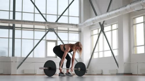 Closeup of Female Powerlifter Preparing to Lift a Barbell with Heavy Weights