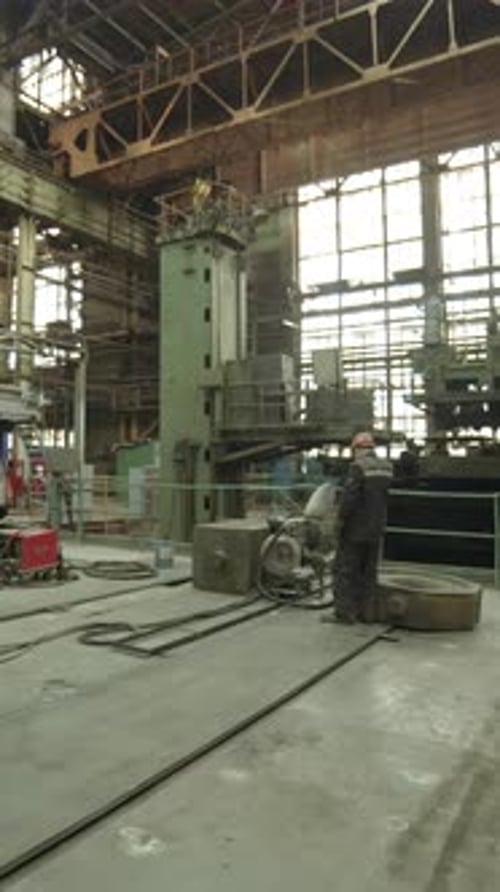 Industrial Worker Walking in Large Metalworking Factory Stock Clip