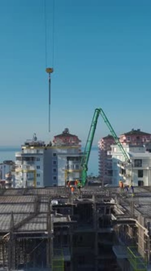 Vertical Video of a Crane Assisting With Material Movement While Workers Assemble Wall Structures
