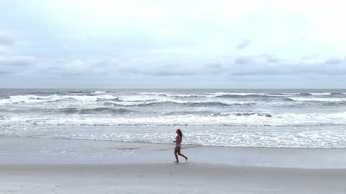 Young Woman Running Along the Ocean in Slow Motion Shot From Above Sport Lifestyle