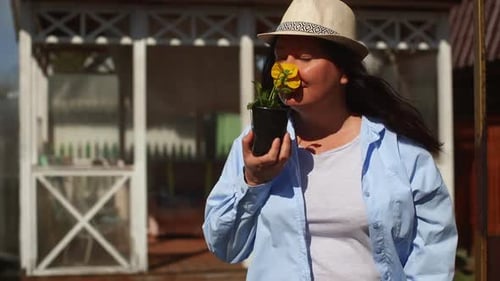 Woman Smells Flower in Garden on Sunny Day