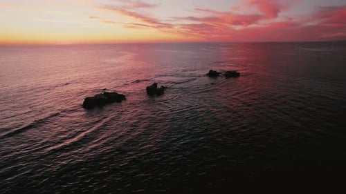 Sunset over rocky coastline at the ocean, highlighting the serene waters and breathtaking sky colors