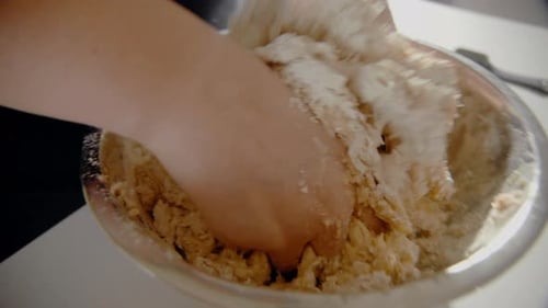 Young Female mixing water and flour in a bowl making dough for a cake in the kitchen at home. detail