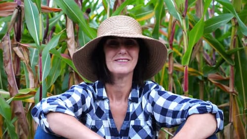 Happy Smiling Female Farmer Looks Into Camera Sitting Near Corn Field Portrait of Adult Tired