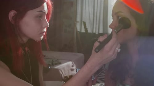 Woman Applying Makeup to Friend in Bedroom