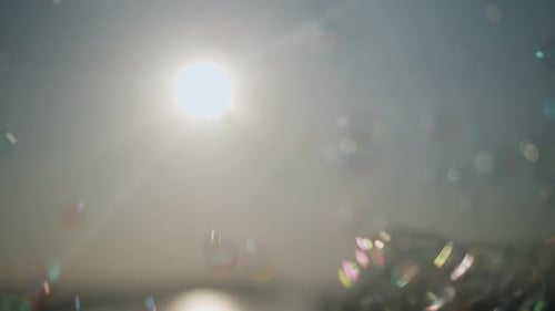 Gros plan de bulles colorées flottant sous un soleil éclatant avec des rayons lumineux