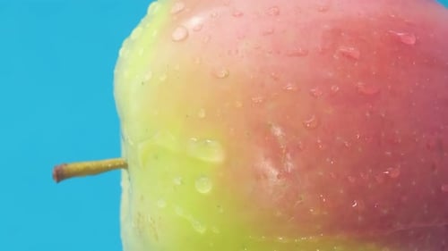 Fresh Red Green Apple on Blue Background Water Drops A Rotating Apple Closeup Vertical Video
