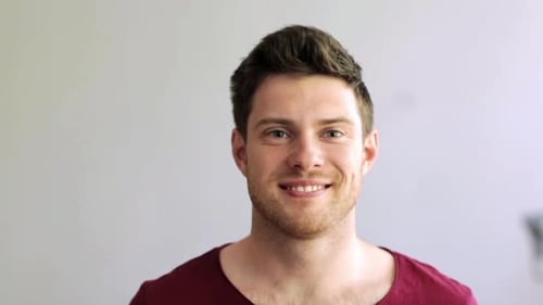 Smiling young man in a maroon t-shirt indoors