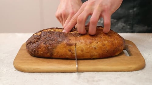 Hands Slicing Delicious Crusty Brown Bread Loaf