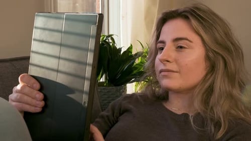 Woman Holding Tablet While Relaxing on Couch
