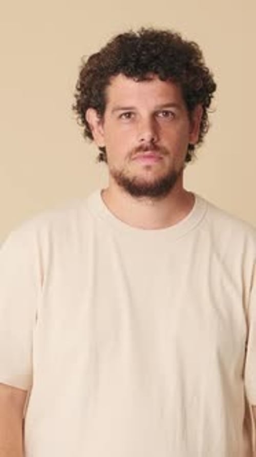 Man rejoices in victory looking at camera isolated in studio on beige background