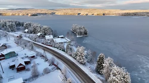 Aerial view of a snowy village by a frozen lake at sunset