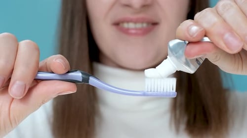 Woman Applying Toothpaste to Toothbrush in Close Up