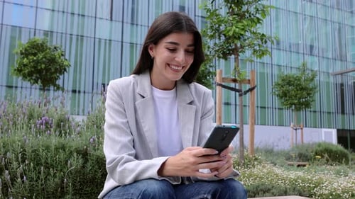 Successful Young Adult Businesswoman Using Smart Phone Over Business Building