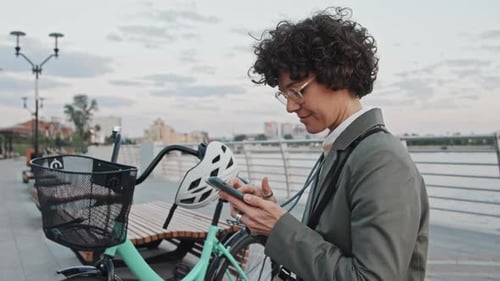 Woman Using Phone Next to Bike