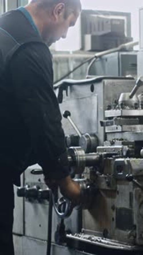 Factory worker operating precision industrial machine in workshop