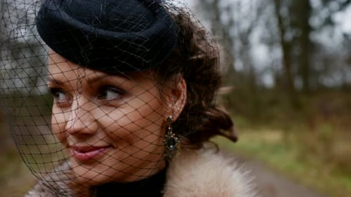 Portrait d'une jeune belle dans un chapeau de style rétro avec voile noir, gros plan du visage d'une femme à l'extérieur