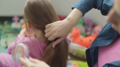 Parent Brushing Child's Hair Indoors at Home