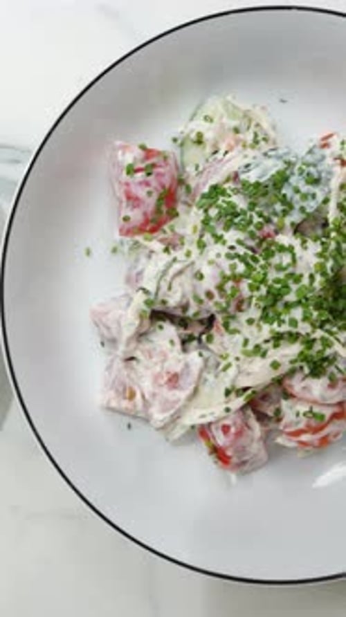 Frische griechische Salatzutaten in einer weißen Schüssel mit Tomaten, Gurken, Feta und Lachs
