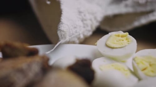 Two Whole Unpeeled Boiled Eggs and Two Slices of Eggs Isolated on a White Background