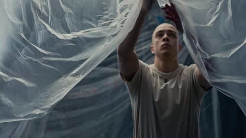 Young Man Preparing for Work in Studio with Plastic Film on Walls