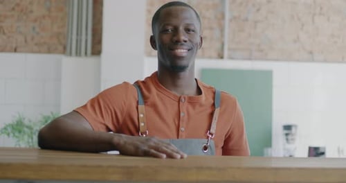 Slow Motion Portrait of African American Man Barista Standing at Counter in Cafe Smiling Looking at