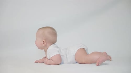 ein Säugling auf weißem Hintergrund beginnt auf dem Bauch zu kriechen.