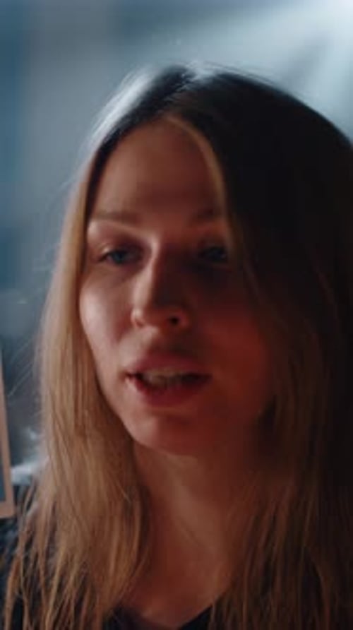 Woman speaking in dark setting holding tarot card