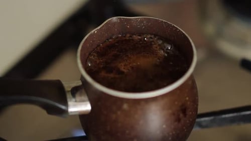 Boiling coffee in a traditional pot on the stove in a cozy kitchen