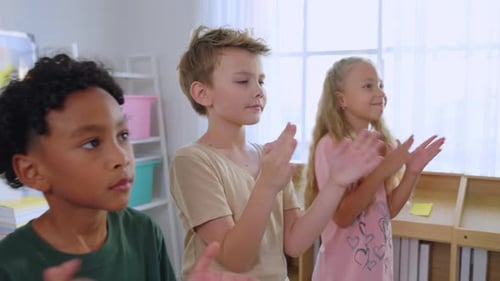 Group of diversity adorable student clapping hands at nursery school.