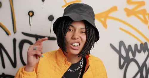 Stylish woman dancing in front of graffiti wall