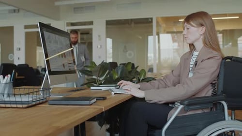 Businesswoman in Wheelchair Working on Computer in Office