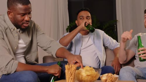 Three friends relaxing, drinking beer and eating snacks
