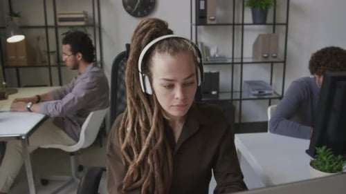 Female Software Engineer in Headphones Working on Computer in Office