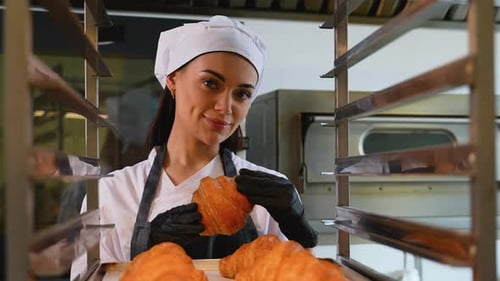 Smiling Chef Holds Fresh Croissant in Bakery Kitchen