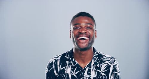 4k video footage of a young man laughing against a grey studio background