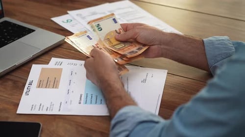 Man Counting Euro Bills at Wooden Desk