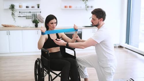 Woman in Wheelchair Exercises with Therapist Assistance