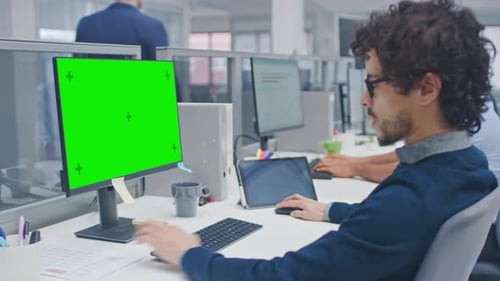 Young Handsome Manager with Curly Hair Works on a Desktop Computer with Green Screen Mock Up. Diver