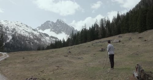 Man With Stick Standing On The Hill Looking At Snowy Dolomites Mountains In Italy. - wide shot