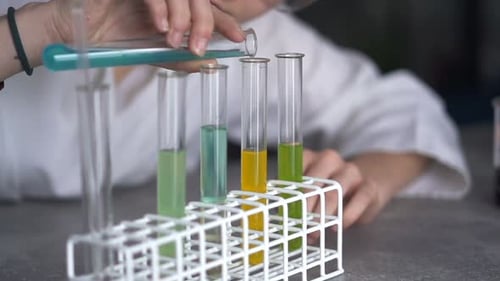 Woman Scientist Pours Blue Liquid into Test Tubes