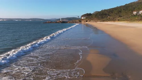 Coastal Serenity: Waves on Sandy Beach with Lighthouse