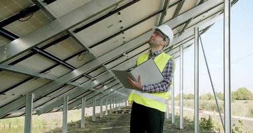 Male Engineer Inspecting Solar Panels