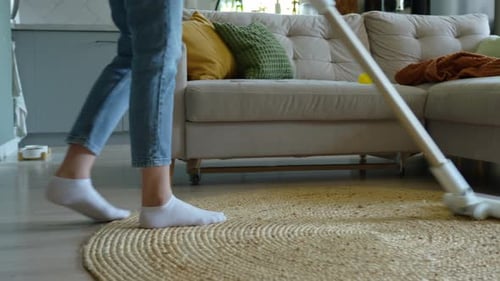 Person vacuuming rug in living room at home