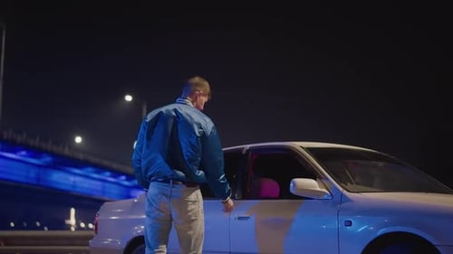 Figure Cautiously Approaches Stationary Vehicle Beneath Glowing Bridge Tentative Encounter Unfolds